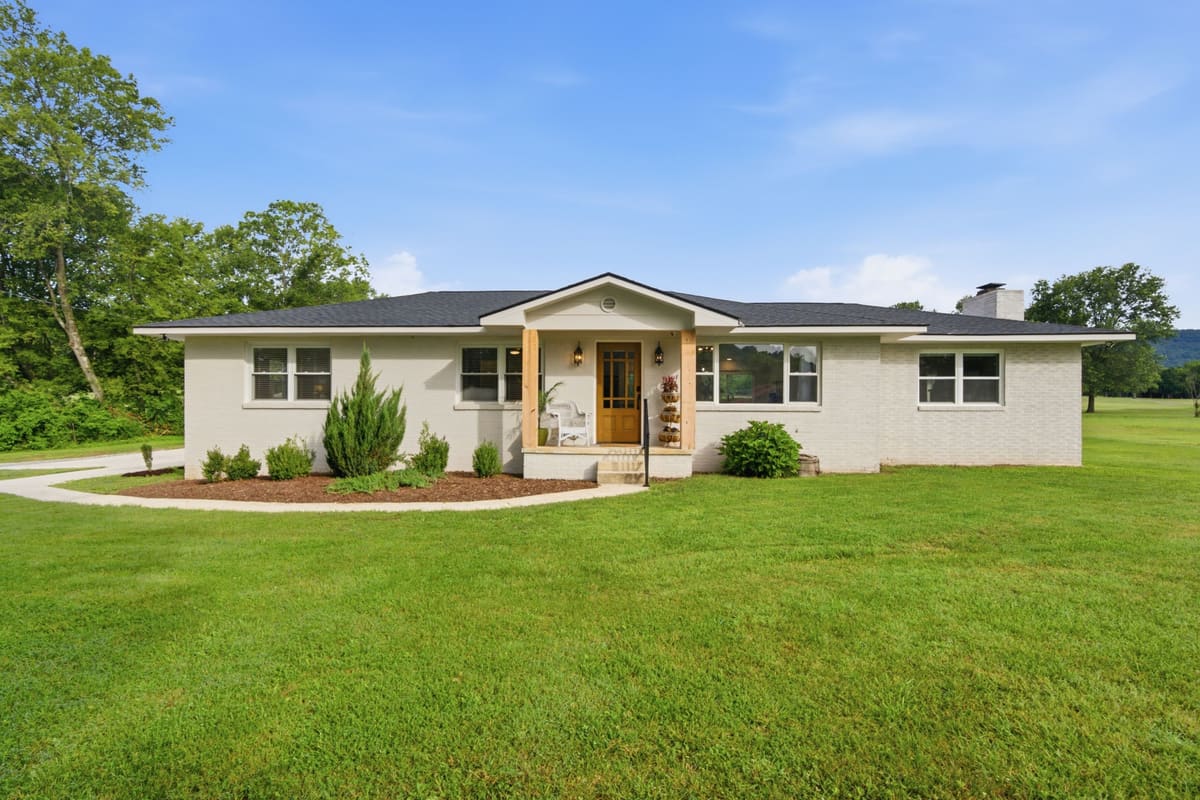 Front of a single-level painted brick home with cedar porch posts and a wide lawn at 338 Highwater Road, Dayton, Tennessee.