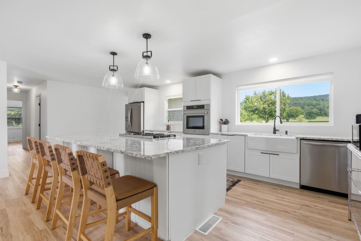 White shaker kitchen with a farmhouse sink under a wide window looking out to the golf course.